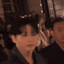 a blurry picture of a man in a suit standing in a crowd of people .