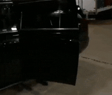 a man with a beard wearing a t-shirt that says `` ugly '' is standing next to a black suv .