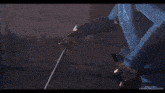 a man in a blue jacket is holding a sword on a brick sidewalk