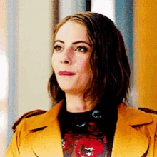 a woman is wearing a yellow jacket and a black shirt with a floral print .