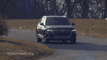 a black audi is driving down the road