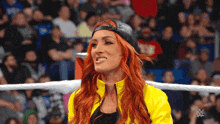 a woman wearing a yellow jacket and a black hat is smiling in front of a crowd