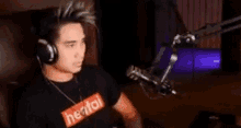 a man wearing headphones is sitting in front of a microphone in a room .