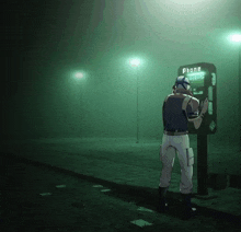 a man stands in front of a phone booth that says phone