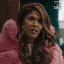 a woman in a pink fur coat and hoop earrings looks angry