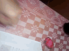 a person 's hand rests on a checkered tablecloth