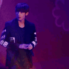 a man in a black jacket is standing in front of a red background with smoke coming out of it .