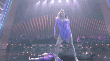 a woman in a purple dress is dancing on a stage