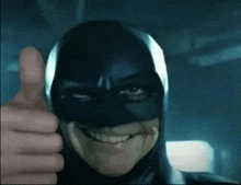 a man wearing a batman mask is giving a thumbs up .