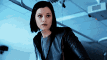 a woman wearing a black leather jacket and a grey sweater