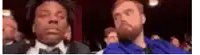 a man with a beard is sitting next to another man in a blue shirt .