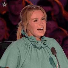 a woman in a green dress stands in front of a microphone and smiles