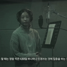 a woman wearing headphones stands in front of a microphone in a recording studio