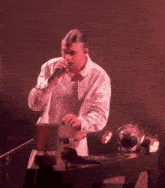a man singing into a microphone with a lamp in the background