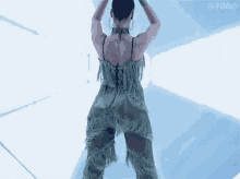 a woman in a fringed dress is dancing in a room with her hands in the air .