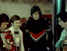 a group of men are standing around a man holding a red accordion