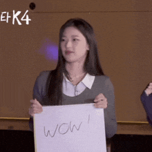 a girl holding a piece of paper that says wow