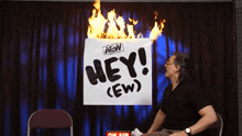 a man sitting in front of a sign that says hey ( ew )