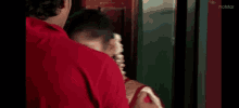 a man in a red shirt is touching the neck of a woman in a red sari .