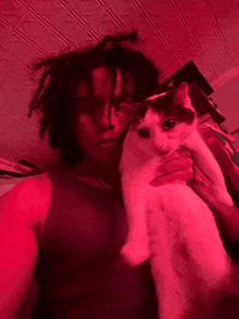 a man with dreadlocks is holding a cat that has a tag that says ' i love you ' on it