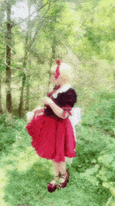 a girl in a red dress is standing in the grass