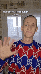 a man wearing a red and blue gucci sweater waves