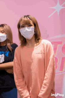 a woman wearing a mask and a pink sweater with the word weekend on it