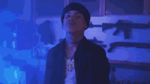 a man with a tattoo on his neck is standing in front of a wall of guns