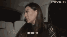 a woman is sitting in the back seat of a car talking .