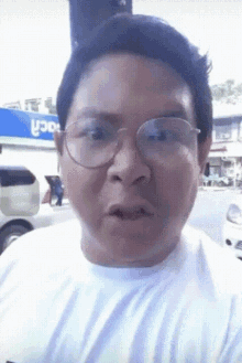 a man wearing glasses and a white shirt is standing in front of a store that says roca