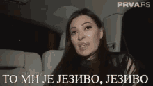 a woman is sitting in the back seat of a car talking in a language other than english .