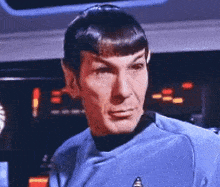 a close up of a man in a blue shirt with a star trek logo on his chest