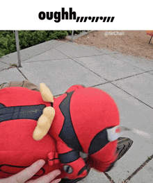 a person is petting a stuffed deadpool on the sidewalk with the caption oughh