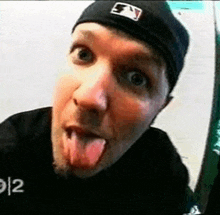 a man wearing a baseball cap is sticking out his tongue .