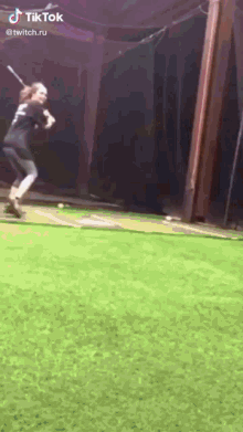 a woman is swinging a baseball bat at a ball on a field .
