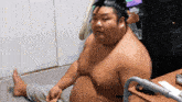 a shirtless man sits on the floor next to a table