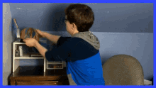 a boy in a blue shirt is standing in front of a shelf