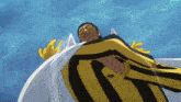 a man wearing a yellow and black striped shirt and a white cape