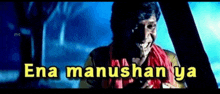 a man with a scarf around his neck is smiling in a dark room with the words ena manushan ya written in yellow .