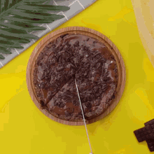 a chocolate pizza on a wooden cutting board with a knife cutting it