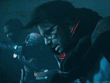 a man with glasses and a scarf around his neck is looking at another man