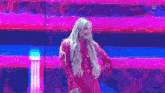 a woman in a red dress is standing on a stage in front of a pink and blue background .