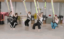 a group of women are hanging from a rope in a room .