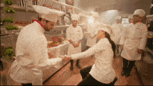 a group of chefs are standing around a woman