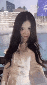 a young woman with long hair is taking a selfie in front of a pool .