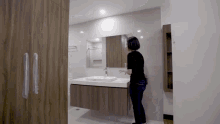 a woman is standing in a bathroom next to a sink