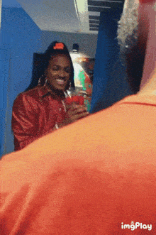 a woman in a red shirt is smiling while holding a red cup