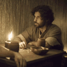 a man is sitting at a table with a lit candle