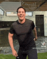 a man wearing a black shirt and black shorts is standing in front of glass