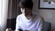 a man in a white shirt is sitting at a table with a fork in his hand .